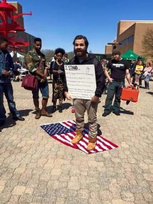 Photo of a protester at Wright State University standing on the American Flag