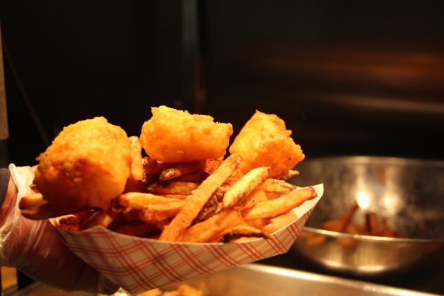 Quincy's Original Fish House cod on a bed of fries with 2 slices of bread.