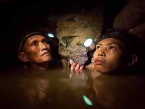 An older miner and a younger boy are chin deep in frigid water 150-meters below the surface as they work a gold mine near Syndicate on the island of Masbate. Image by Larry C. Price. Philippines, 2012.